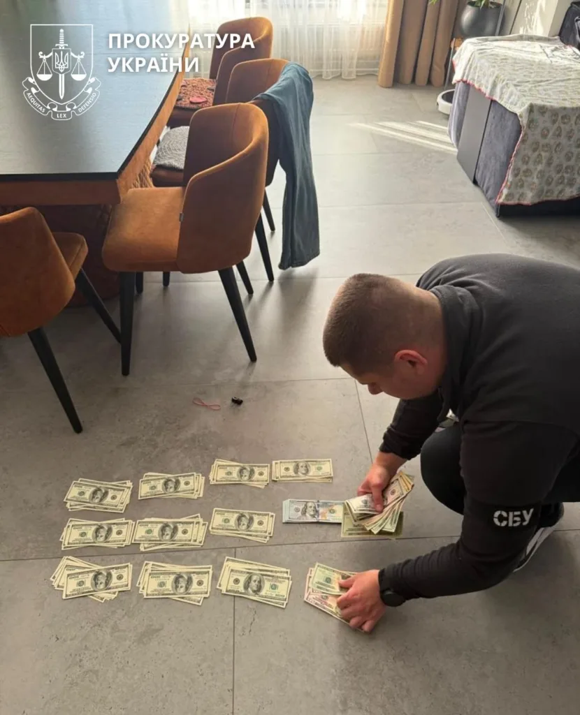 Слідчий рахує долари під час обшуку