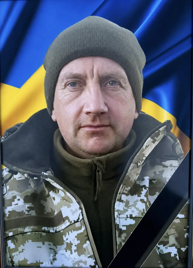 Військовий у камуфляжі перед прапором України