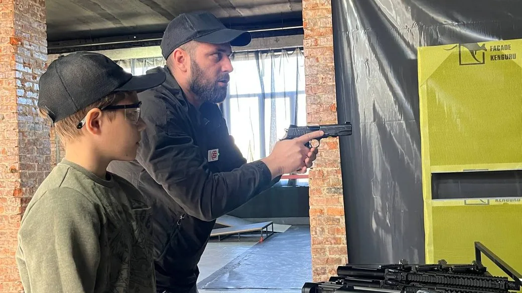 Інструктор навчає хлопчика стрільбі з пістолета
