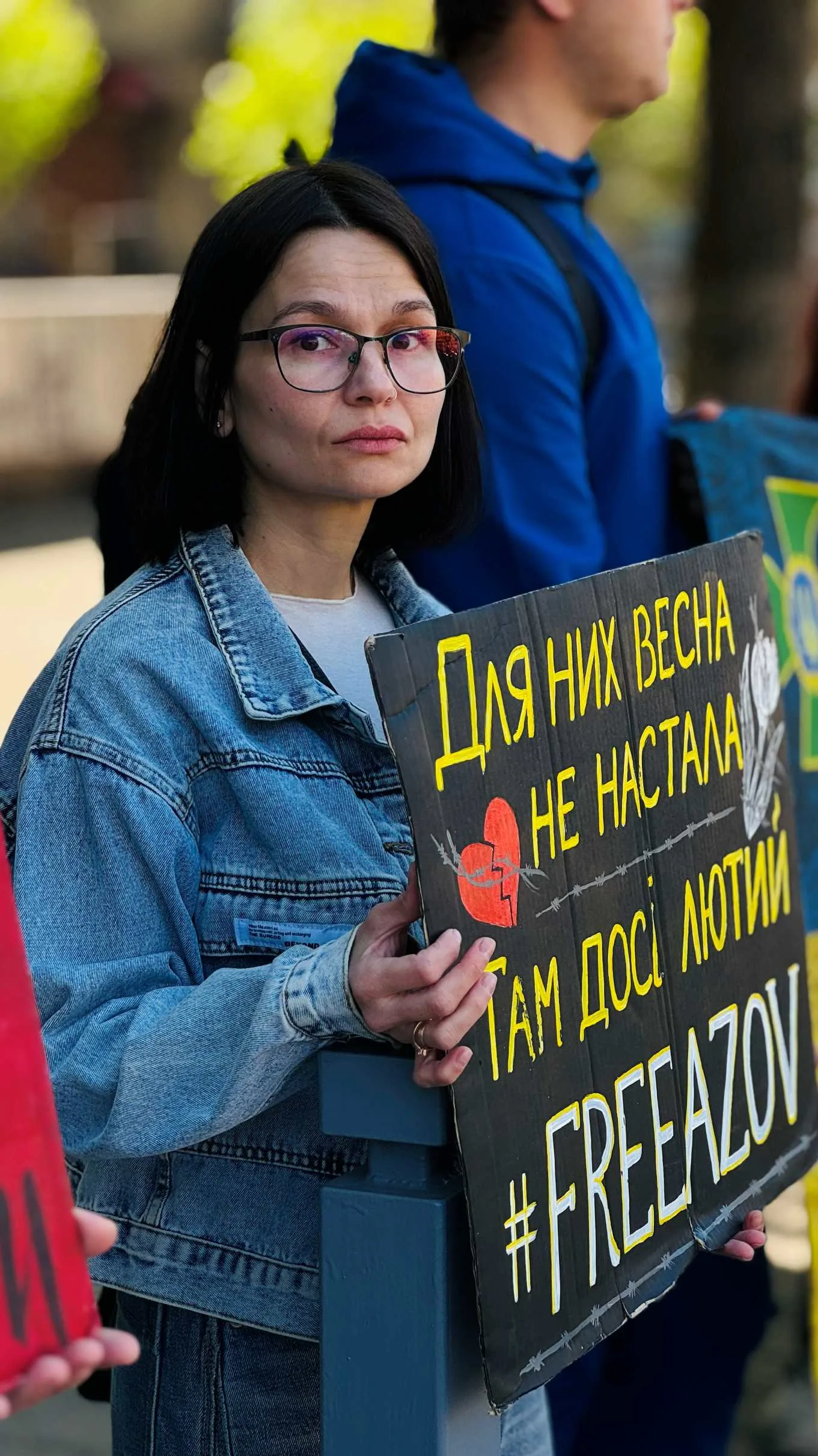 Жінка тримає плакат із написом #FreeAzov