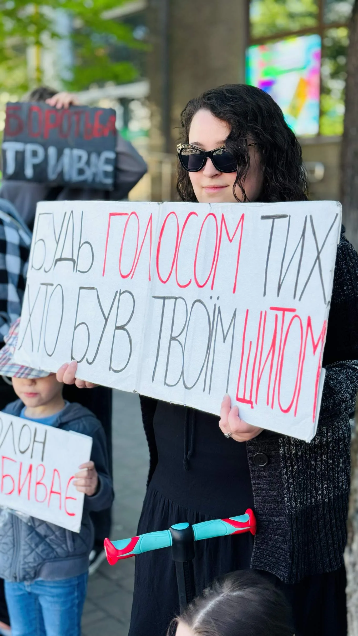 Жінка тримає протестний плакат українською мовою