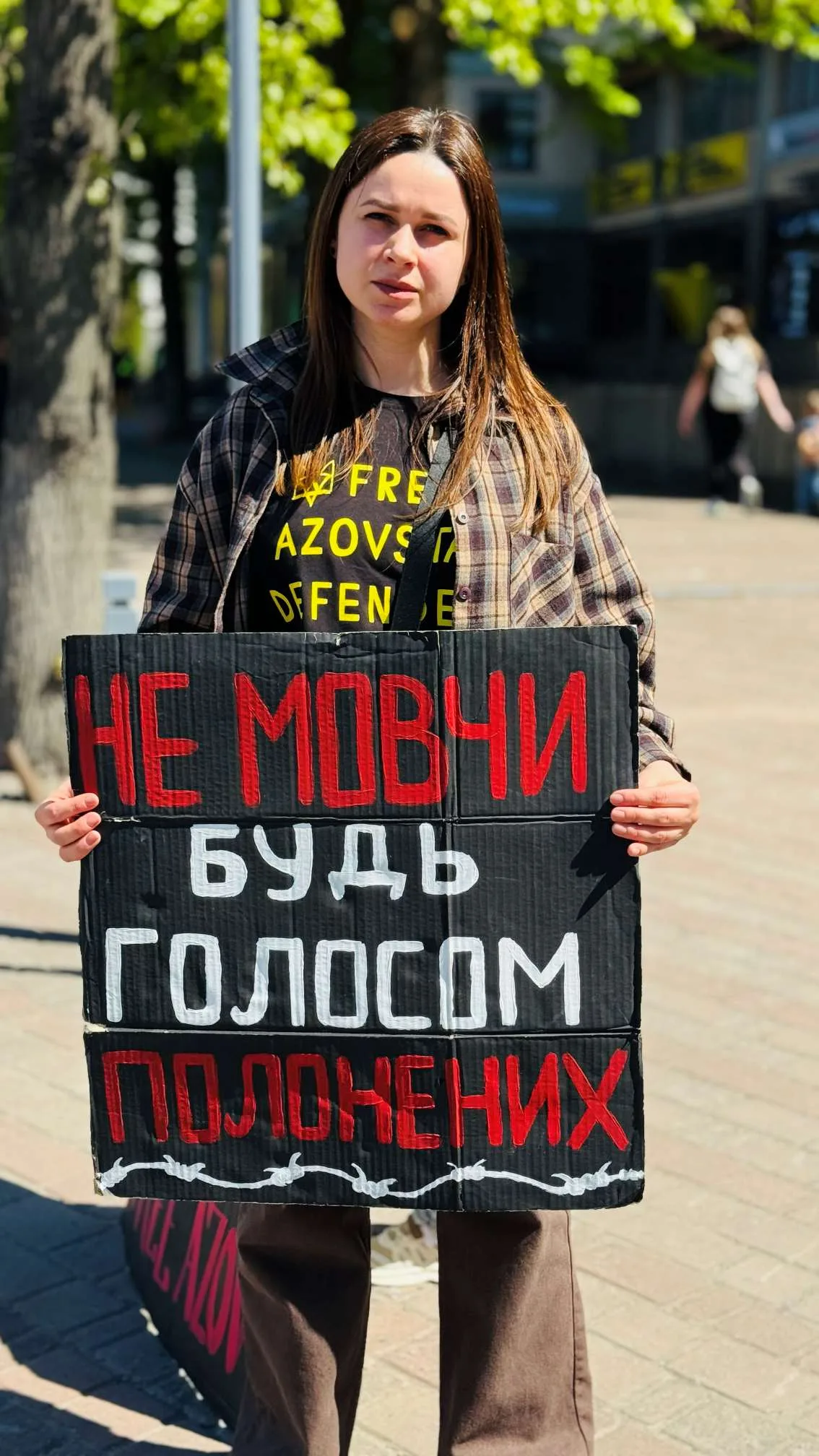 Жінка тримає плакат із закликом до підтримки полонених