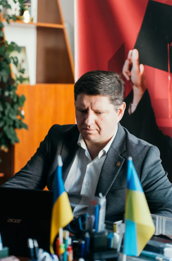 Чоловік працює за ноутбуком з прапорами України