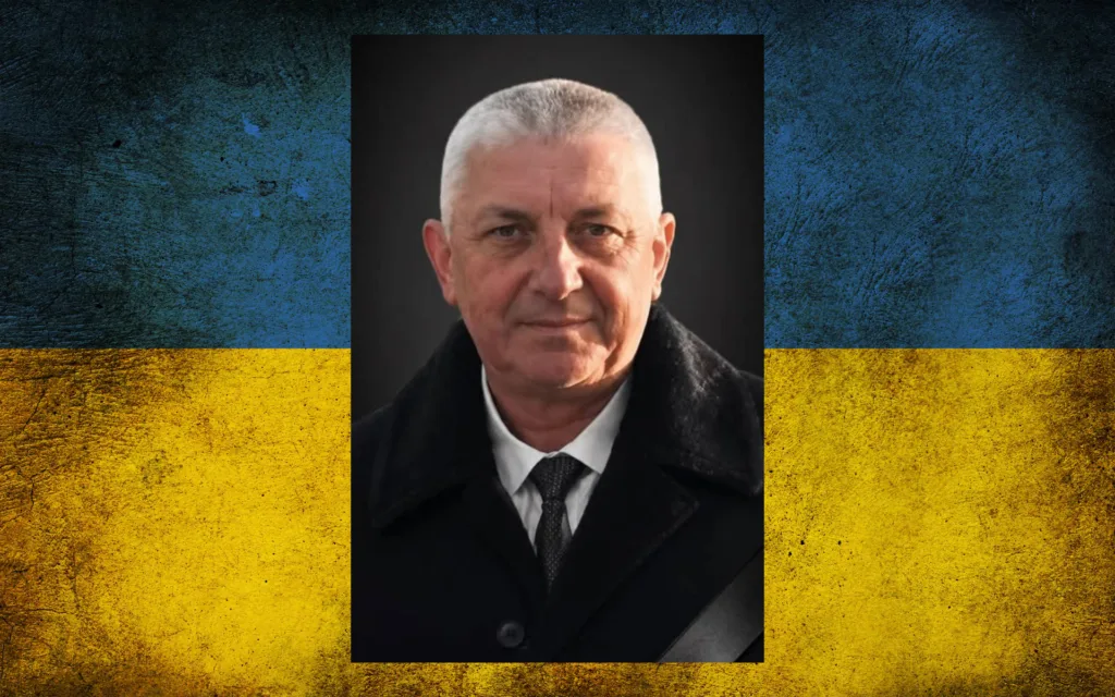 Чоловік у чорному пальті на тлі прапора України