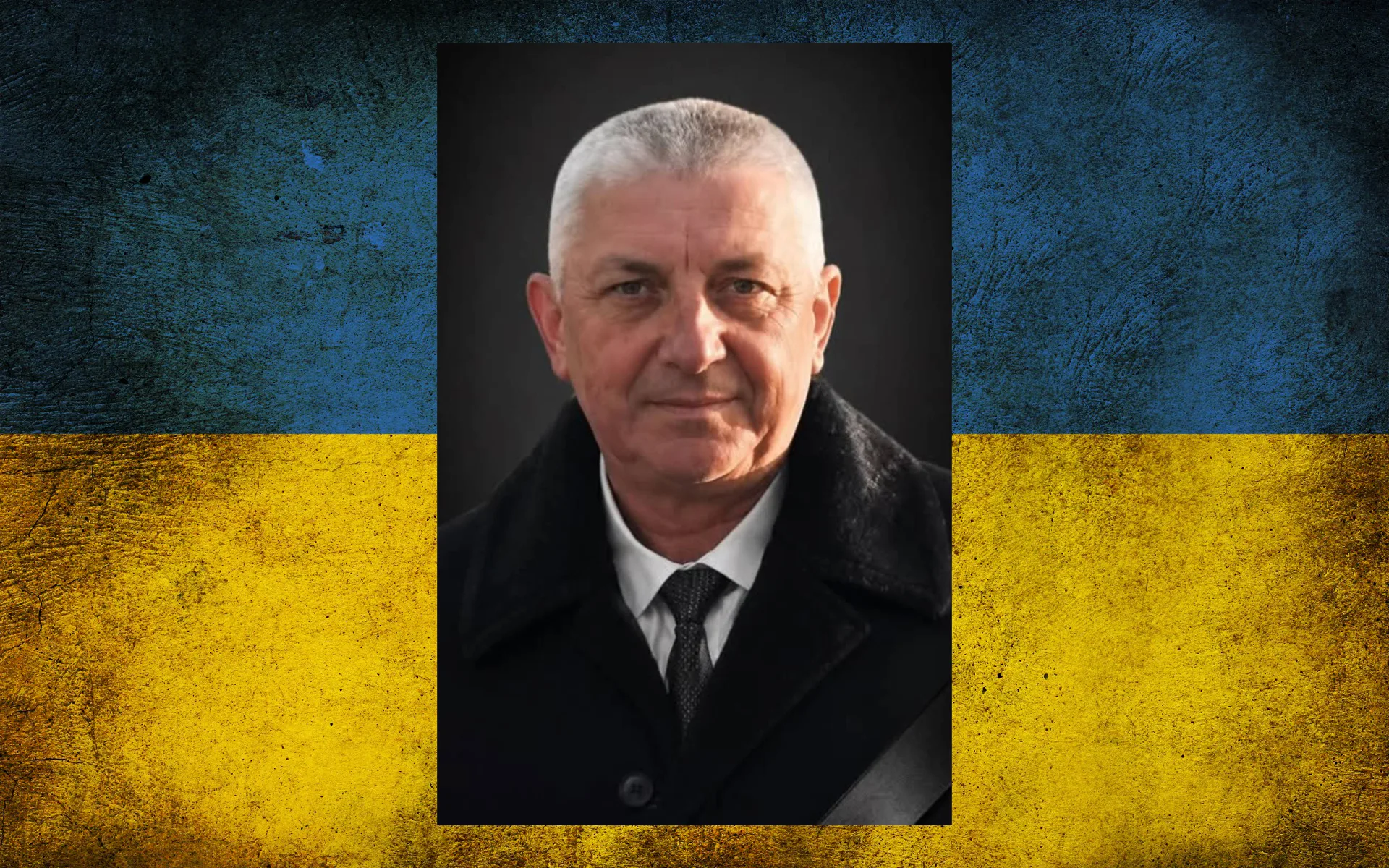 Чоловік у чорному пальті на тлі прапора України