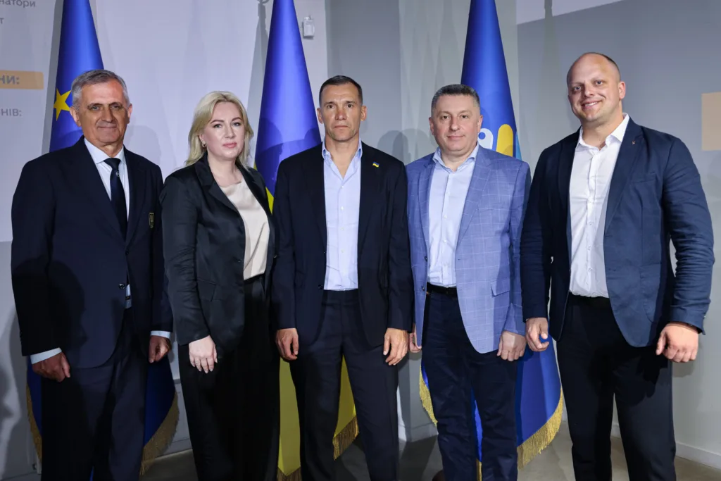 Група людей перед українськими прапорами