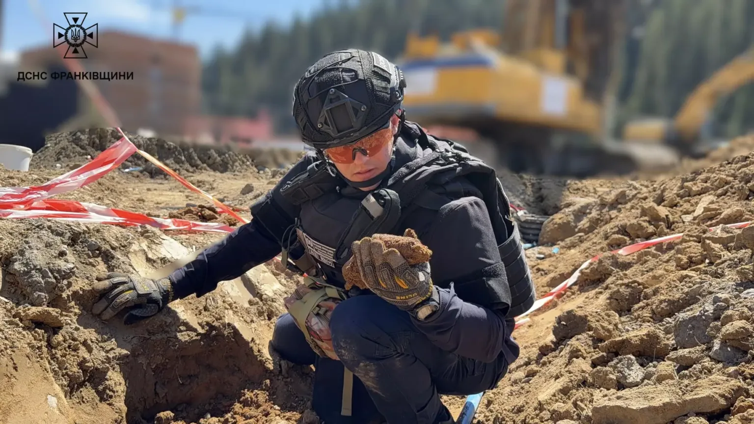 Рятувальник ДСНС оглядає вибухонебезпечний предмет на розкопках