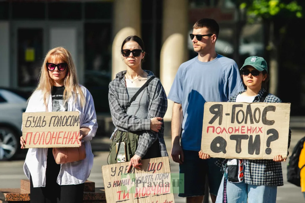 Люди на мітингу з плакатами підтримки полонених