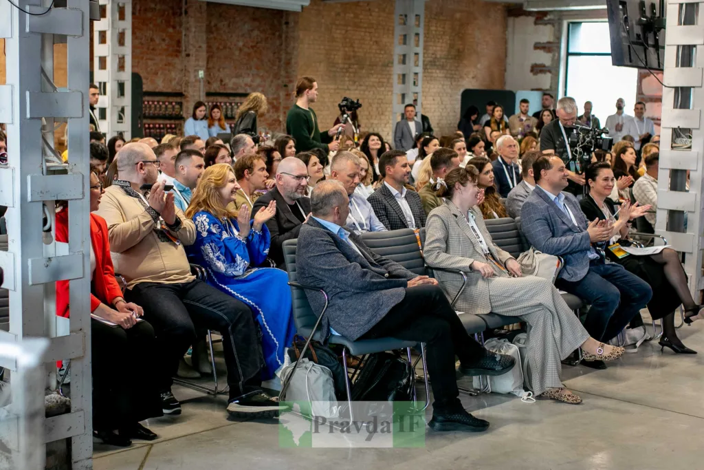 Люди на конференції аплодують доповідачу
