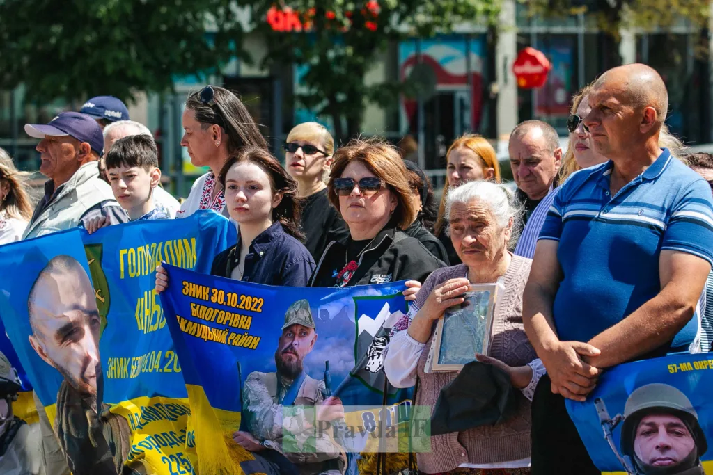 Люди тримають банери на вшануванні захисників України