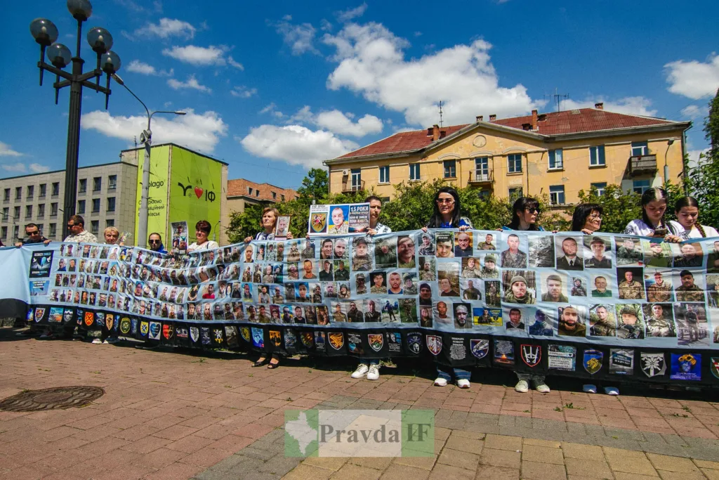 Люди тримають банер із фотографіями українських захисників