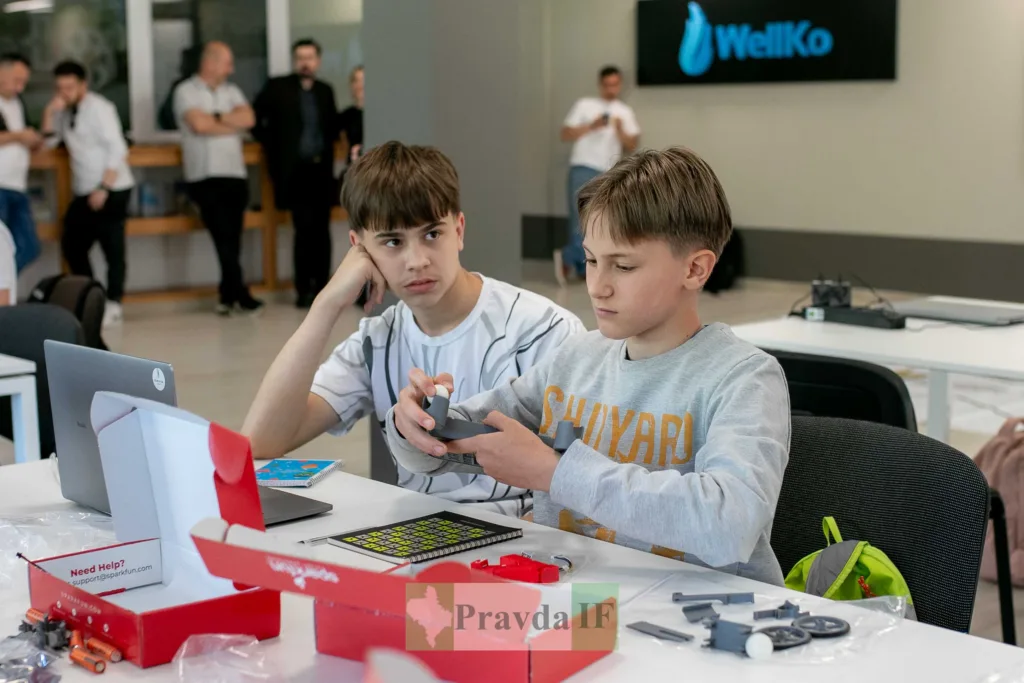 Двоє підлітків збирають робототехнічний проєкт у класі
