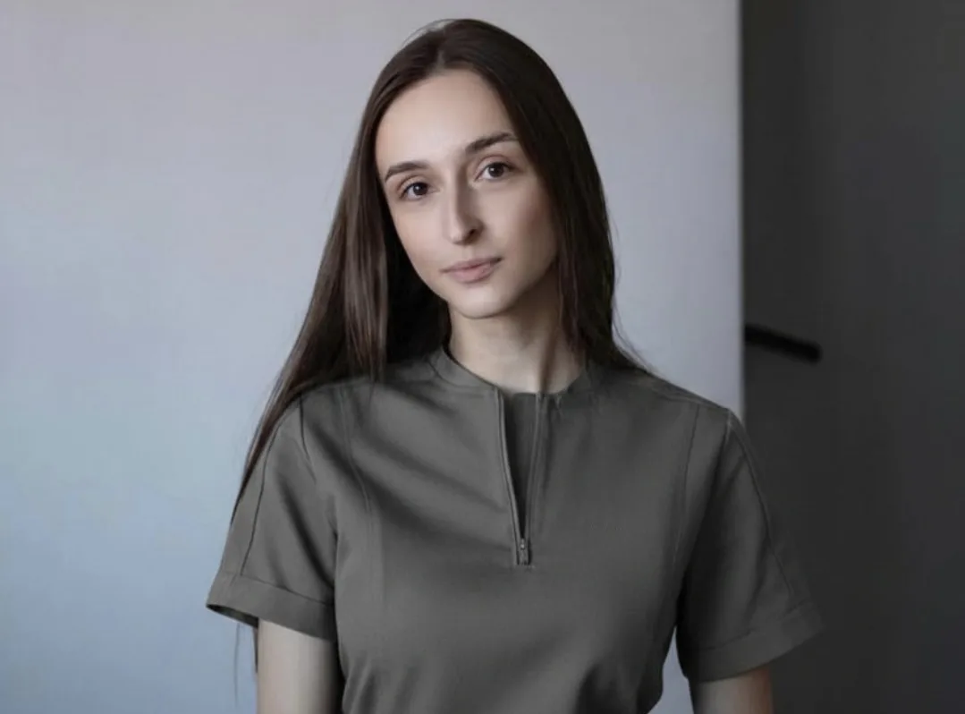 Жінка з довгим волоссям у сірій сорочці