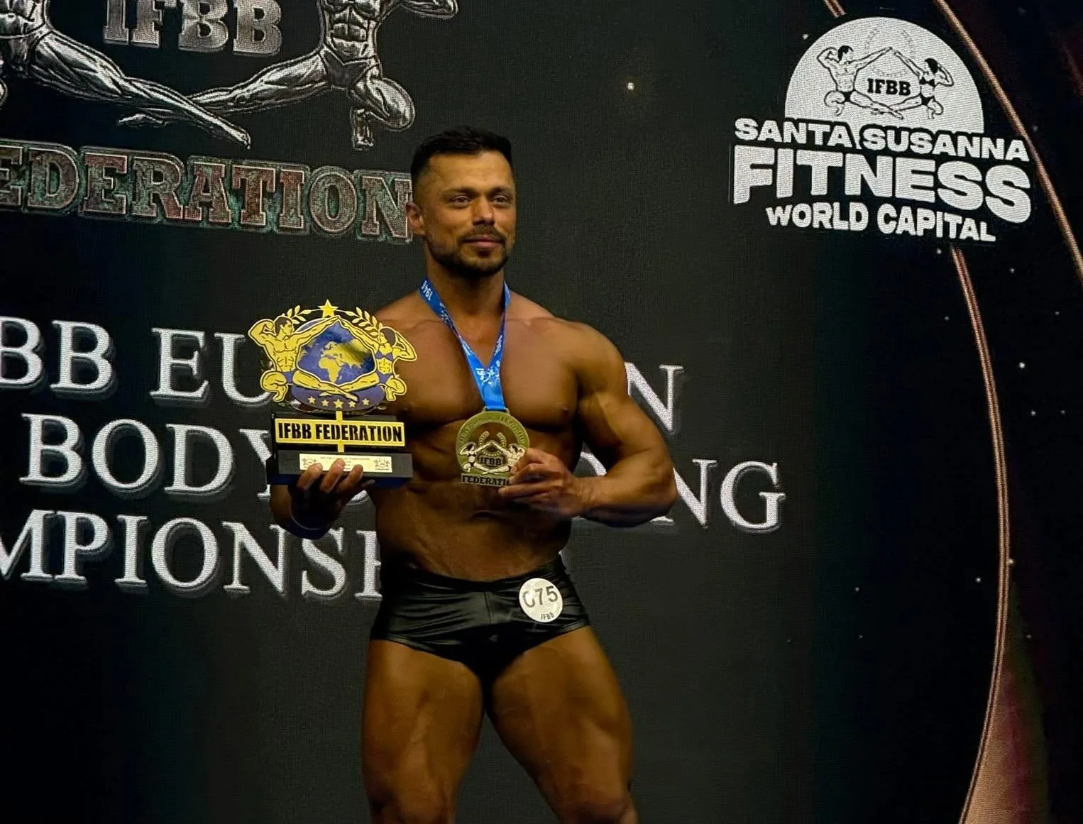 Бодібілдер з кубком на сцені IFBB чемпіонату