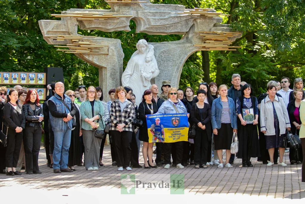 Люди вшановують пам'ять загиблого воїна біля монумента