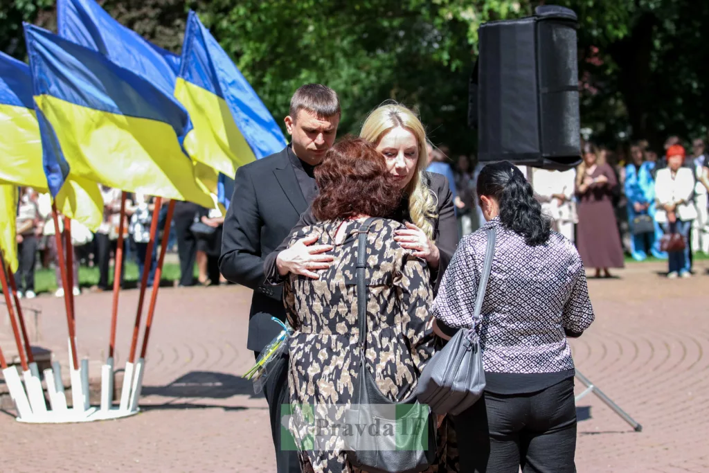Люди обіймаються під українськими прапорами на церемонії