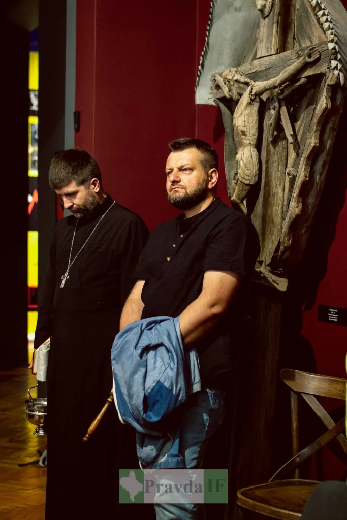 Двоє чоловіків біля дерев'яного розп'яття в музеї