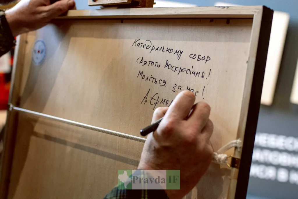 Людина підписує зворотний бік картини