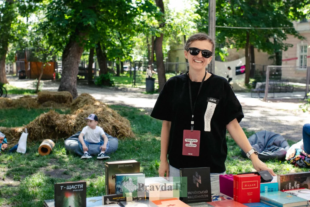 Жінка біля столу з книжками на вуличному ярмарку
