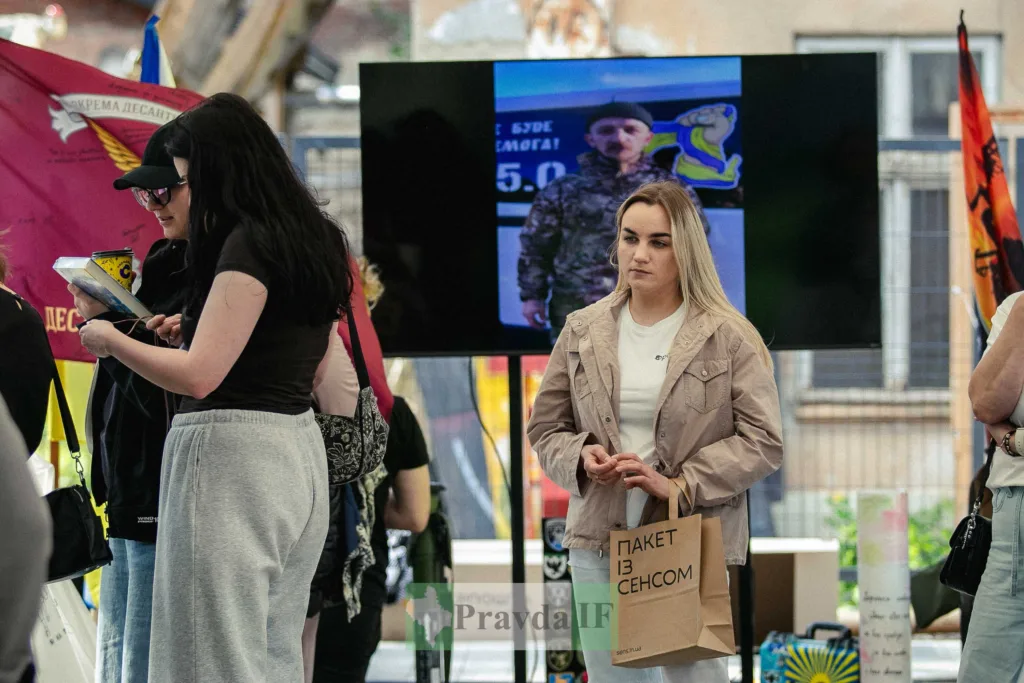 Люди на виставці з прапорами та екранами