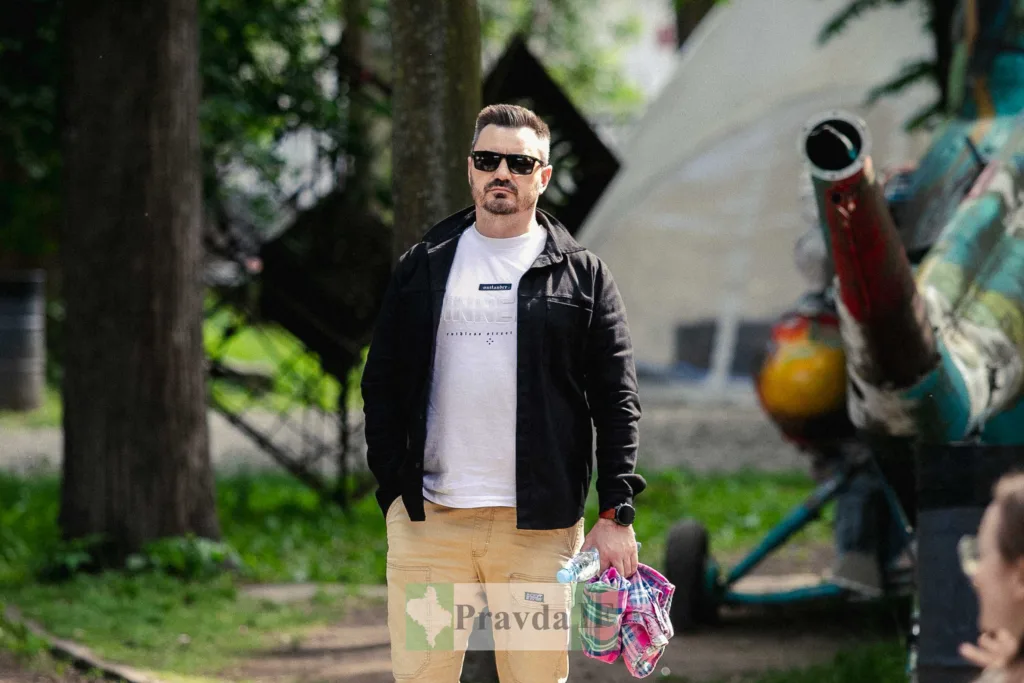 Чоловік у парку тримає речі в руках