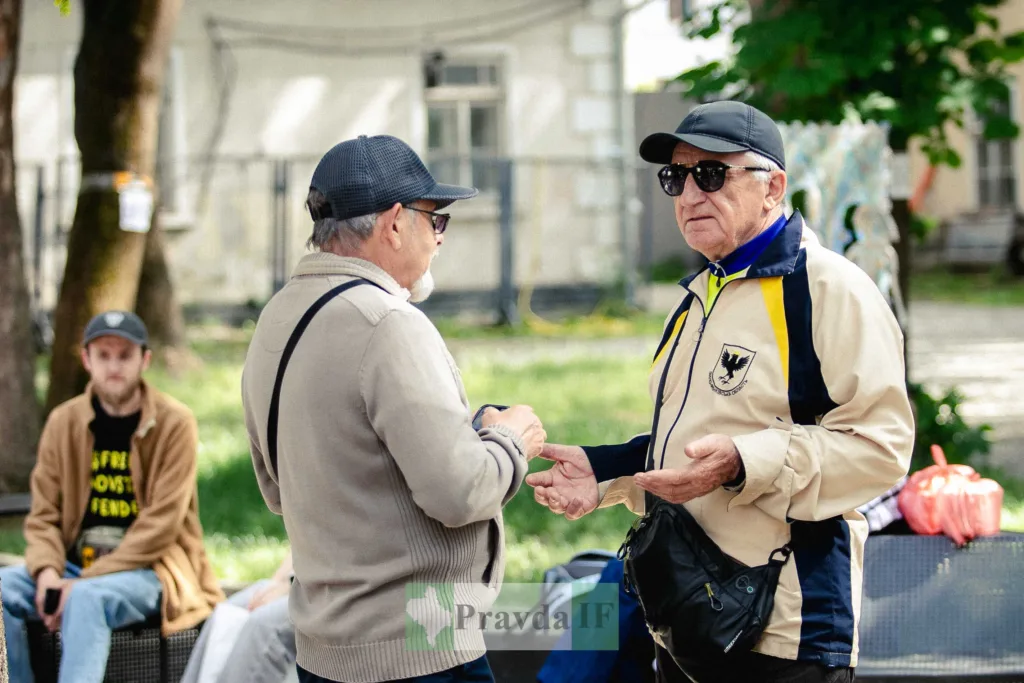 Двоє літніх чоловіків розмовляють у міському парку