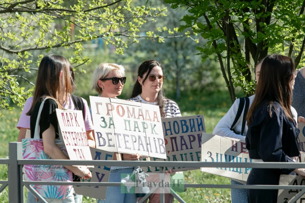 Люди тримають плакати на екологічному мітингу в парку