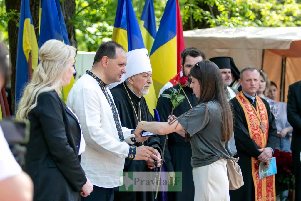 Церемонія вручення квітки біля українських прапорів