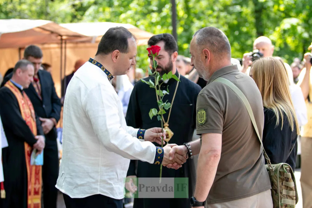 Чоловік у вишиванці передає троянду військовому