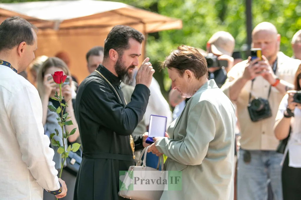 Священник вручає медаль жінці на вулиці