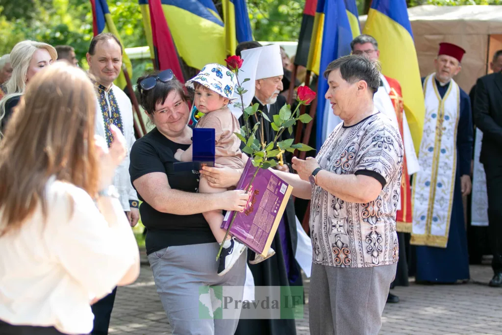 Жінка з дитиною отримує квіти на церемонії