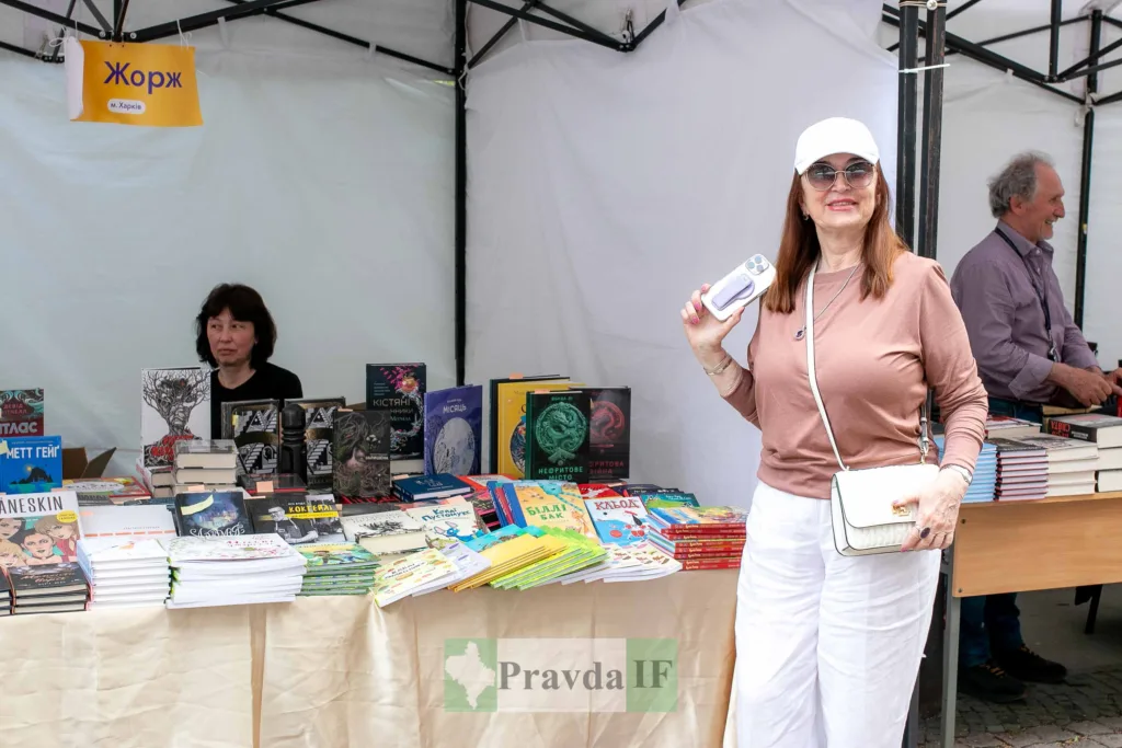 Жінка на книжковому ярмарку біля стенду видавництва