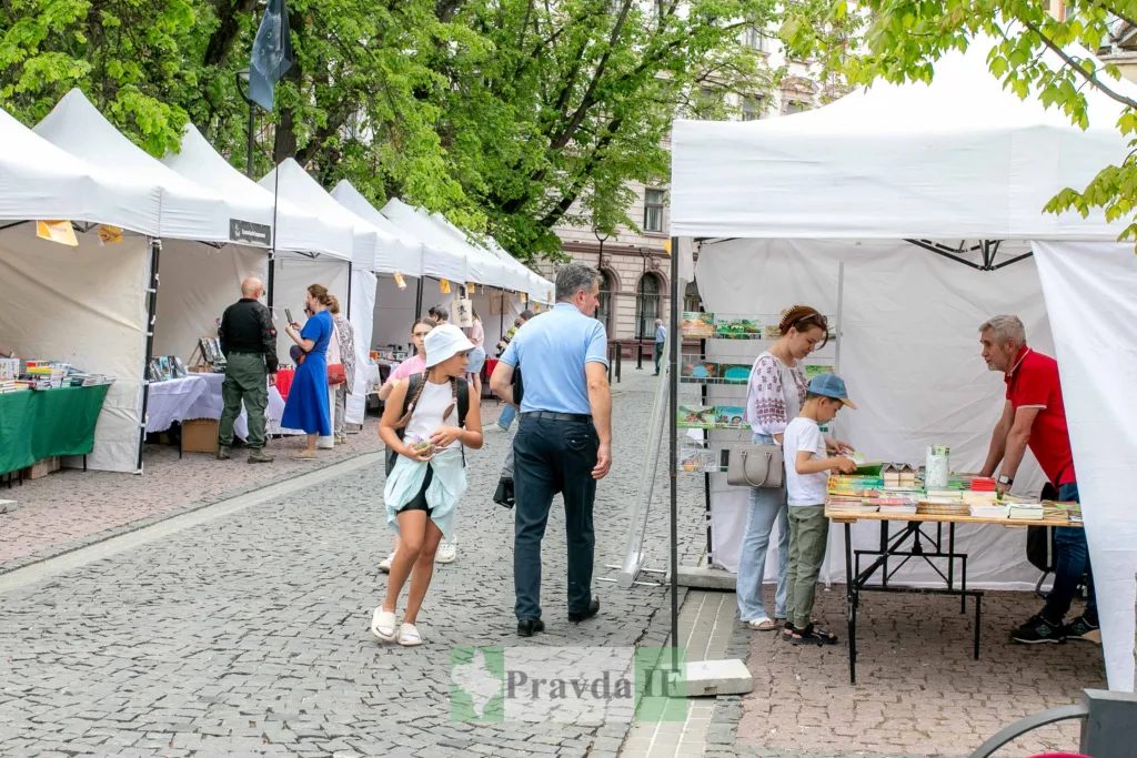 Люди на книжковому ярмарку під білими наметами
