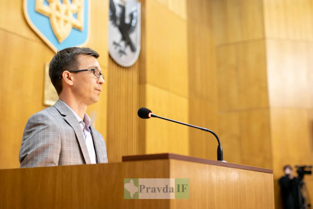 Чоловік виступає на трибуні у залі засідань