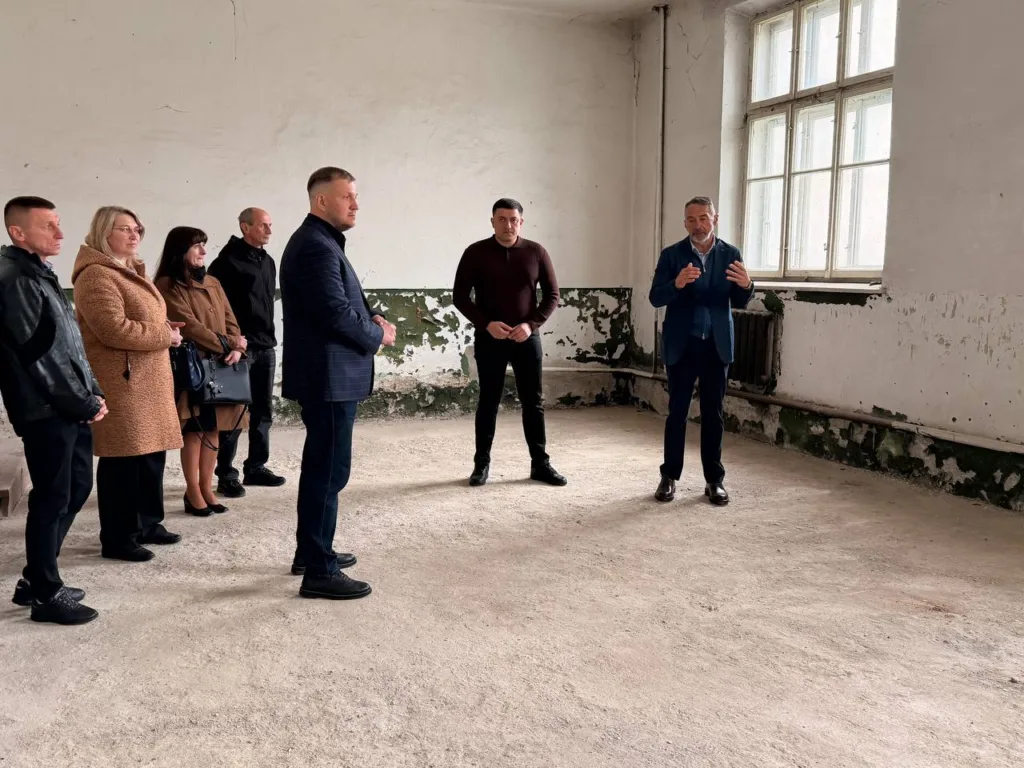 Люди оглядають старе приміщення з облущеними стінами