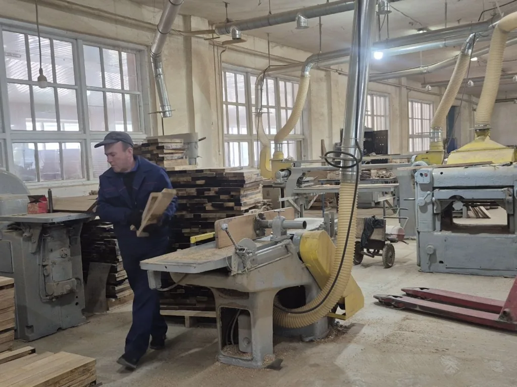 Працівник обробляє деревину на столярному виробництві