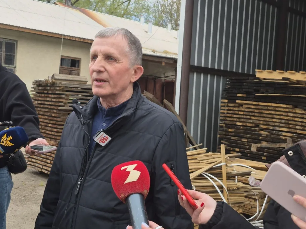 Чоловік дає інтерв'ю біля складу деревини