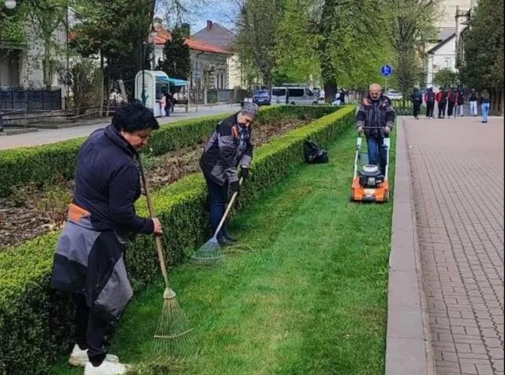 Працівники прибирають та косять траву в парку