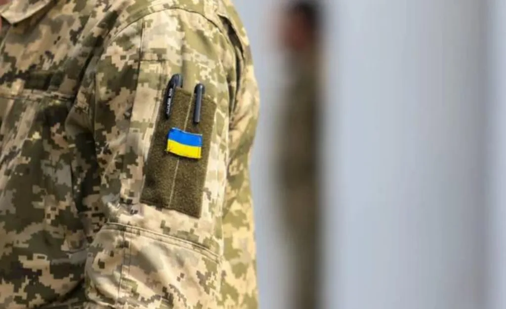Український військовий у камуфляжі з прапором України