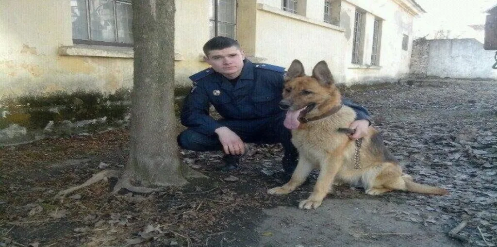Поліцейський з німецькою вівчаркою на подвір’ї