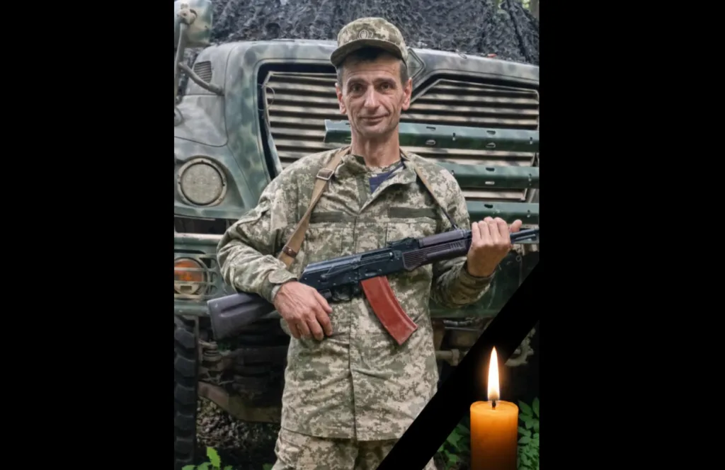 Український військовий з гвинтівкою біля вантажівки