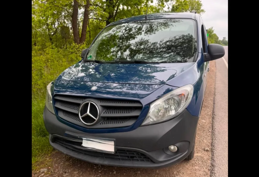 Синій мікроавтобус Mercedes припаркований біля лісу