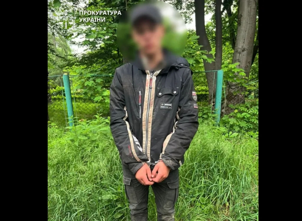Затримана особа на вулиці біля зеленого паркану