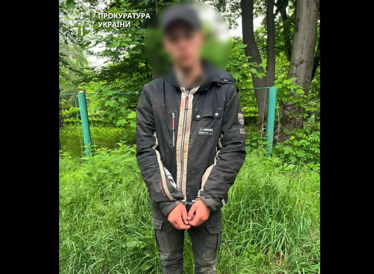 Затримана особа на вулиці біля зеленого паркану