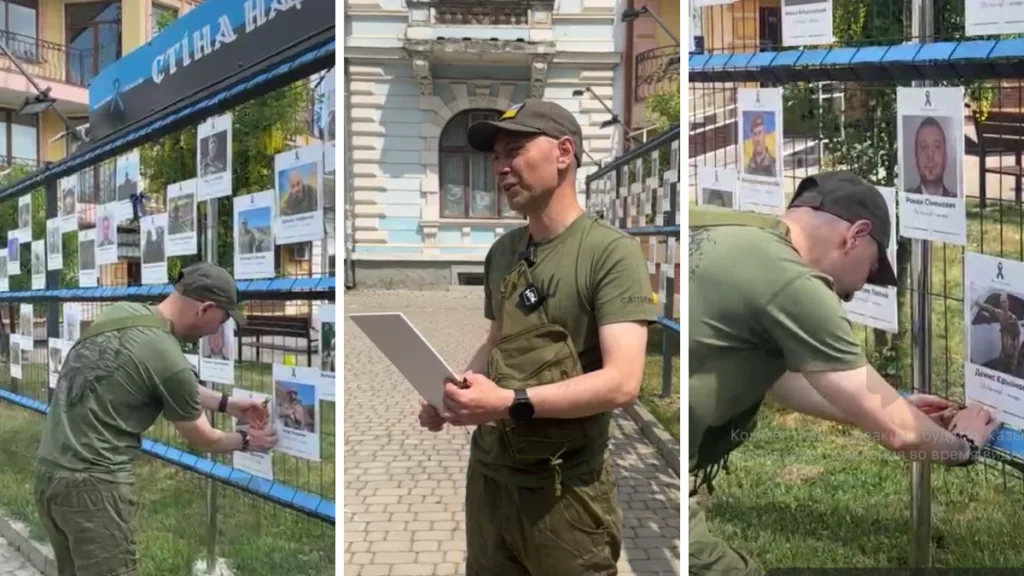 Чоловік розміщує фото військових на стіні пам’яті