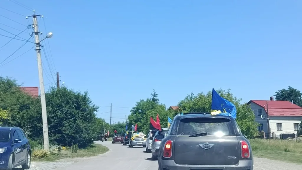 Автоколона з українськими прапорами на сільській дорозі