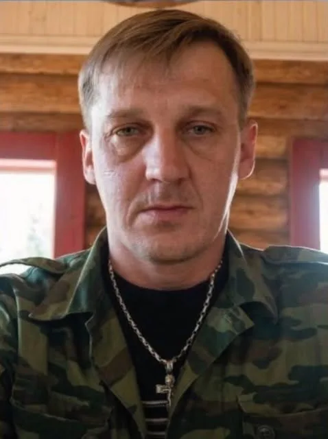 Чоловік у камуфляжній сорочці дивиться в камеру