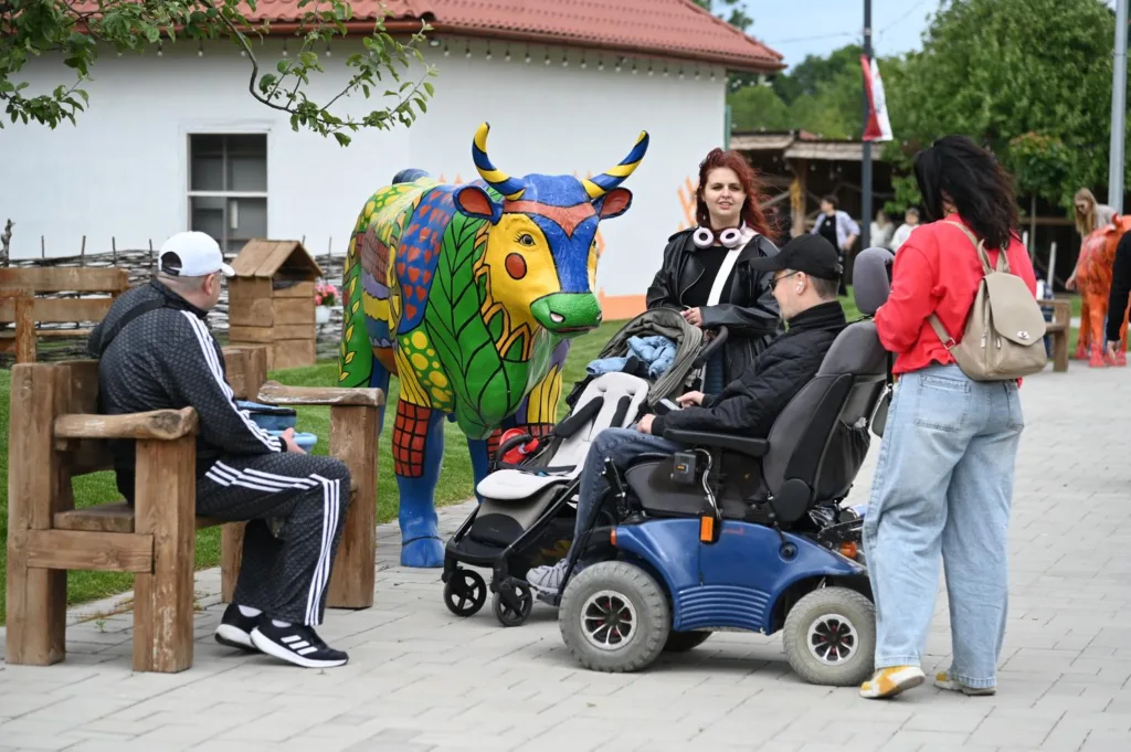 Люди біля яскравої статуї корови на вулиці
