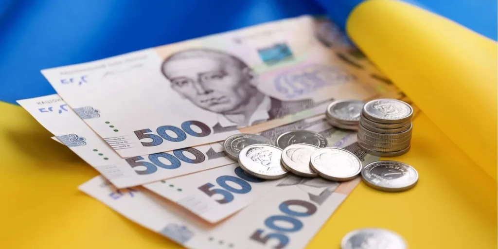 Українські гривні та монети на прапорі України