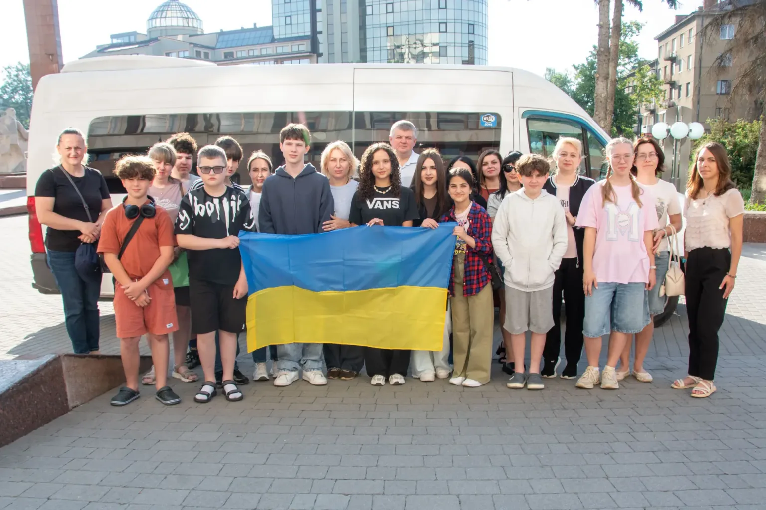 Група людей з українським прапором біля мікроавтобуса